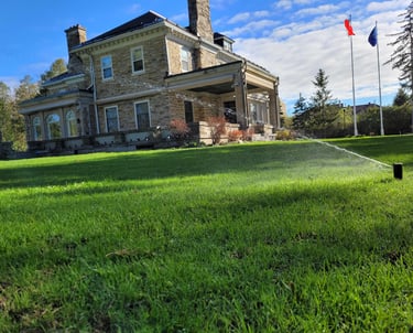 Large estate featuring professional lawn care and active sprinkler system for a lush landscape