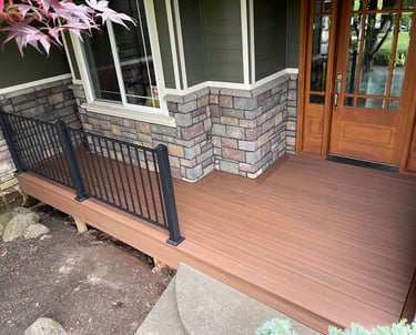 Professional front porch deck installation with modern black metal railings and stone accents.