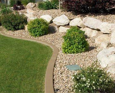 Landscape gravel bed on a hillside with large decorative rocks and low-maintenance plants