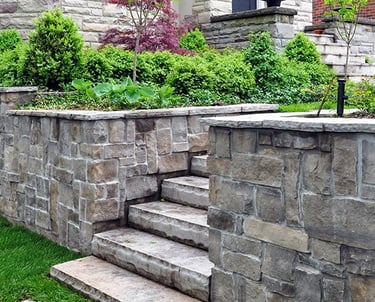 Natural stone retaining wall with integrated steps and garden beds.