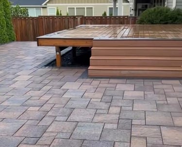 Custom multi-level wooden deck integrated with a modern interlocking stone patio base.