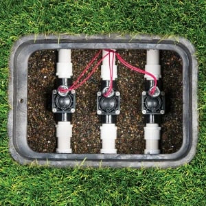 Underground irrigation valve box with three professional solenoid valves for zone control.