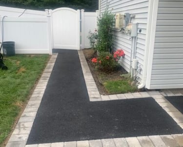 Fresh asphalt walkway with decorative stone paver borders.