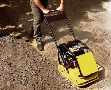 Gas-powered plate compactor ensuring a solid and level sub-base for patio installation.