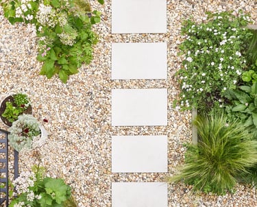 Aerial view of decorative river gravel walkway with square modern pavers and garden planters.