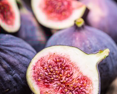 Fresh ripe purple figs sliced open showing a sweet red interior on a rustic wooden table.