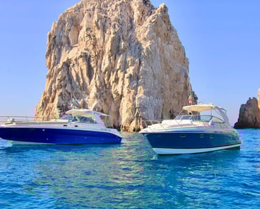 Luxury motor yachts cruising past the iconic El Arco rock formation in Cabo San Lucas.