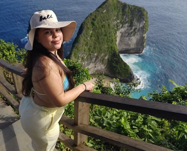 A woman in a Bali sun hat overlooking the scenic Kelingking Beach cliffs in Nusa Penida.
