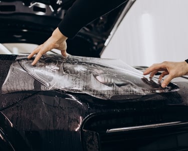 Technician installing vinyl wrap on vehicle hood