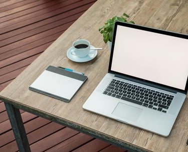 ordinateur portable ouvert sur une table avec une tasse à café et une ardoise veleda