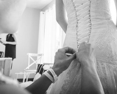 seance d'ajustement de robe de mariée: vue sur les mains de la couturière qui ajuste le laçage.