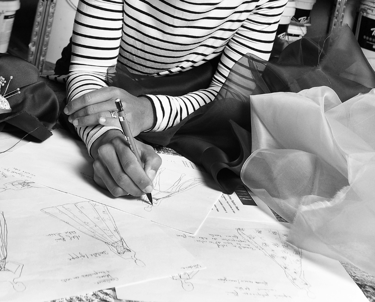 Creatrice qui dessine des robes de mariées, entourée d'échantillons de tissus