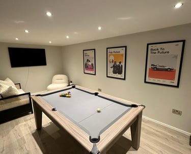 Modern game room featuring a luxury grey pool table and framed movie posters on the wall.