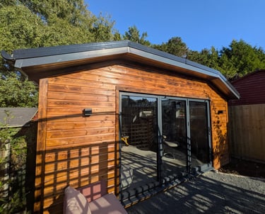 A modern insulated wooden garden gym with anthracite grey bifold doors in a garden