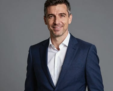 Professional studio headshot portrait of a Moldovan sports executive man in his late 40s, wearing a tailored navy blue suit and white shirt, friendly confident expression, modern grey background.