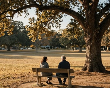 Photography of a serene outdoor counseling session in a North American park, two people talking on a bench under a large oak tree, golden afternoon light, feeling of trust and peace, colors include golden sand and slate blue.