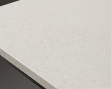 Close-up of polished white marble slabs with subtle gray veining stacked neatly in a sunlit warehouse.