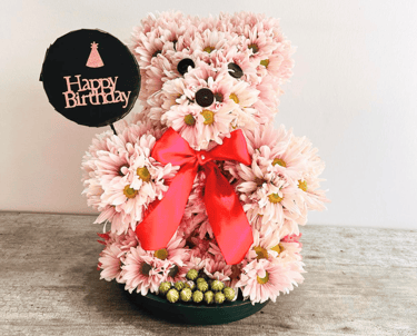 Oso de feliz cumpleaños elaborado con flores. Margaritas rosas