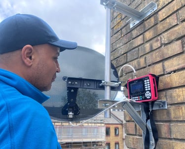 a man in a blue jacket and a red satellite meter installing a sky dish