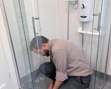 a man kneeling down on the ground repairing a shower