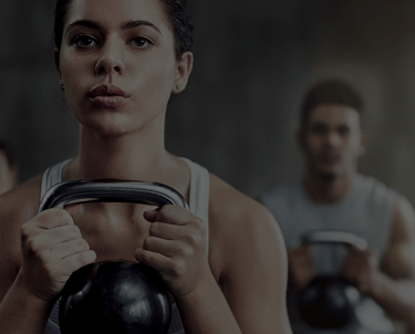 A man and a woman using a kettlebell to do a squat