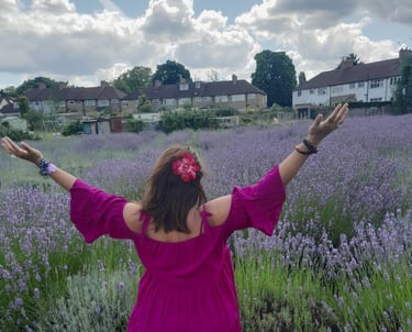 Image of the back of Sheila Cristina in a lavender field in London.  In the distance is houses. 