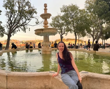 a woman sitting on the ledge of a fountain