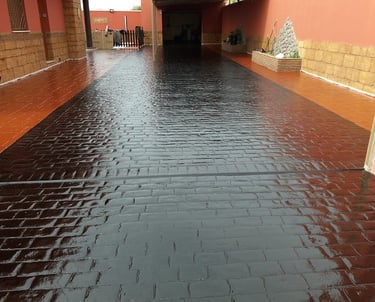 Superficie de hormigón decorativo con acabado de resina y pintura en tonos oscuros, ideal para entradas y patios.
