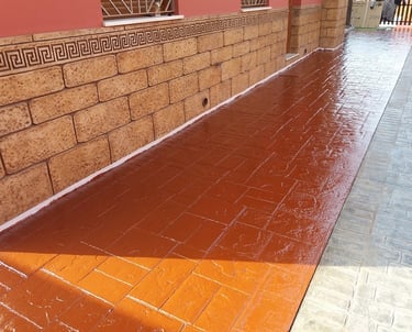 Hormigón impreso en color rojo con acabado brillante, ideal para exteriores elegantes y duraderos.