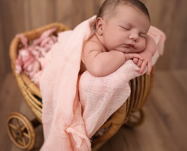 Photo de nouveau né qui dort dans une petite poussette en rotin, un instant d'émotion et de douceur