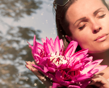 a woman holding a pink flower in her hands