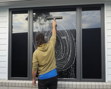 a man is standing in front of a window with a squeegee