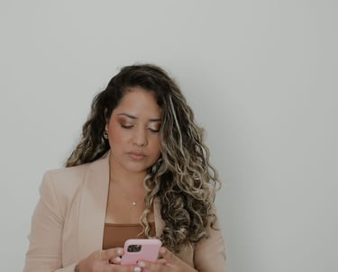 Mulher de Cabelo cacheado de blazer, é a esteticista chamada Janaina Mota