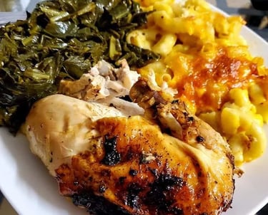 Baked chicken dinner served with creamy macaroni and cheese and slow-cooked collard greens.