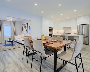Modern open concept kitchen and dining room with a wood table and white cabinets.