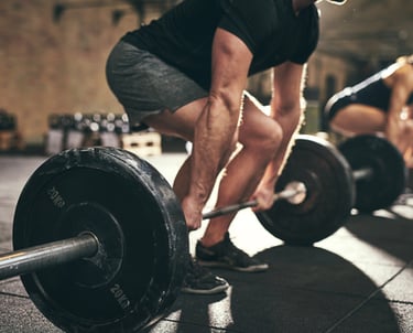 A man performing a heavy barbell deadlift during a strength training workout at a gym.