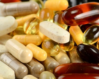A variety of dietary supplement capsules and vitamin pills in different colors and sizes.