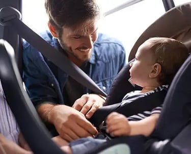 a man and a baby in a car seat