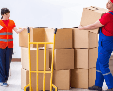 a man and woman moving boxes in a living room