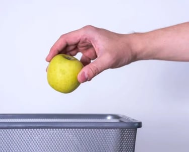 Hand tossing spoiled apple into trash can