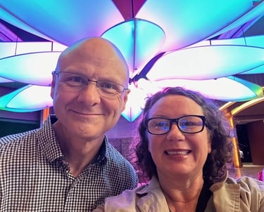 man and woman owners smiling under a flower light fixture