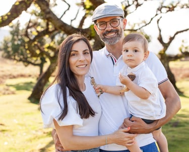 Toddler son standing between mother and father during outdoor family photography session at Fanal Fo