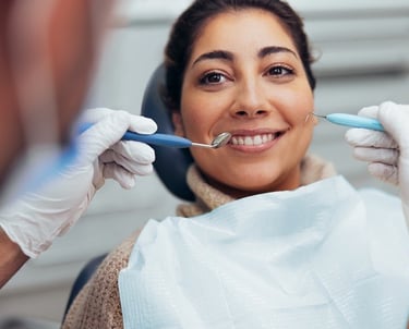 Smiling woman receiving a dental checkup and cleaning at a professional clinic.