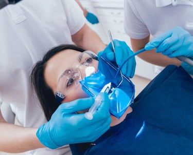 A female patient undergoes a professional root canal procedure with a blue dental dam and syringe.