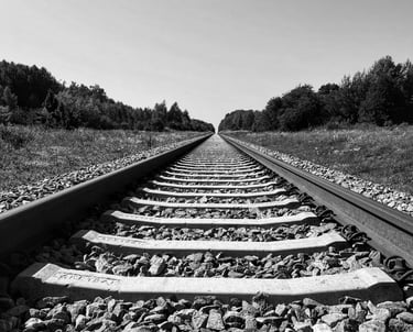 A monochrome image of a railroad track stretching into the distance