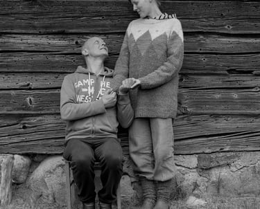 A couple seated on a chair against a wooden wall