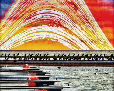 A row of boats docked in a marina, with calm water reflecting the vessels and surrounding scenery