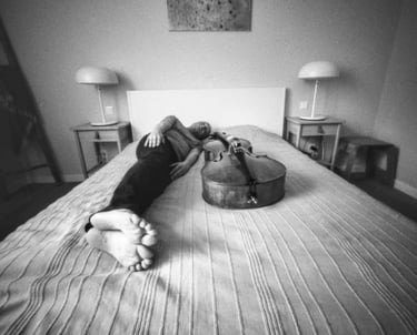 Musician relaxing on bed with cello