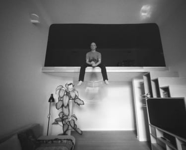 A man sitting in a room, holding cello captured through a pinhole