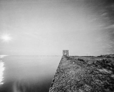 A monochrome image of a waterfront building, showcasing its architectural beauty and serene location